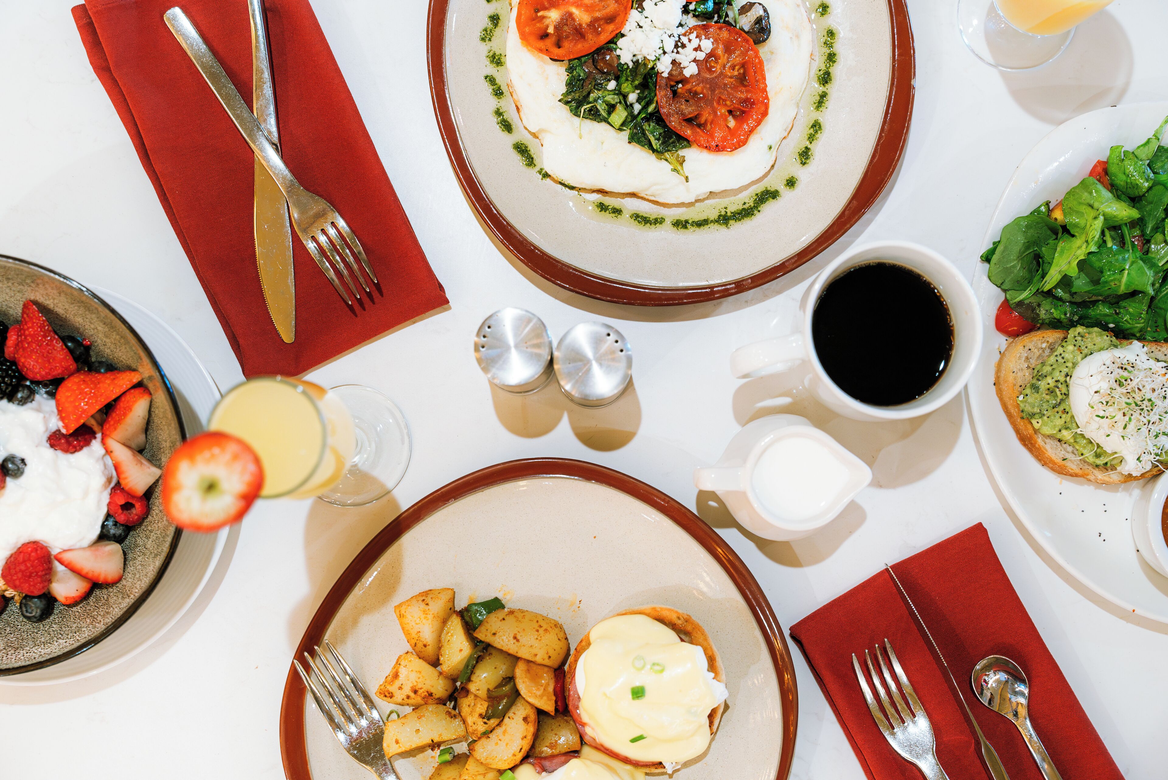 A breakfast setting with plates of food, utensils, and condiments.