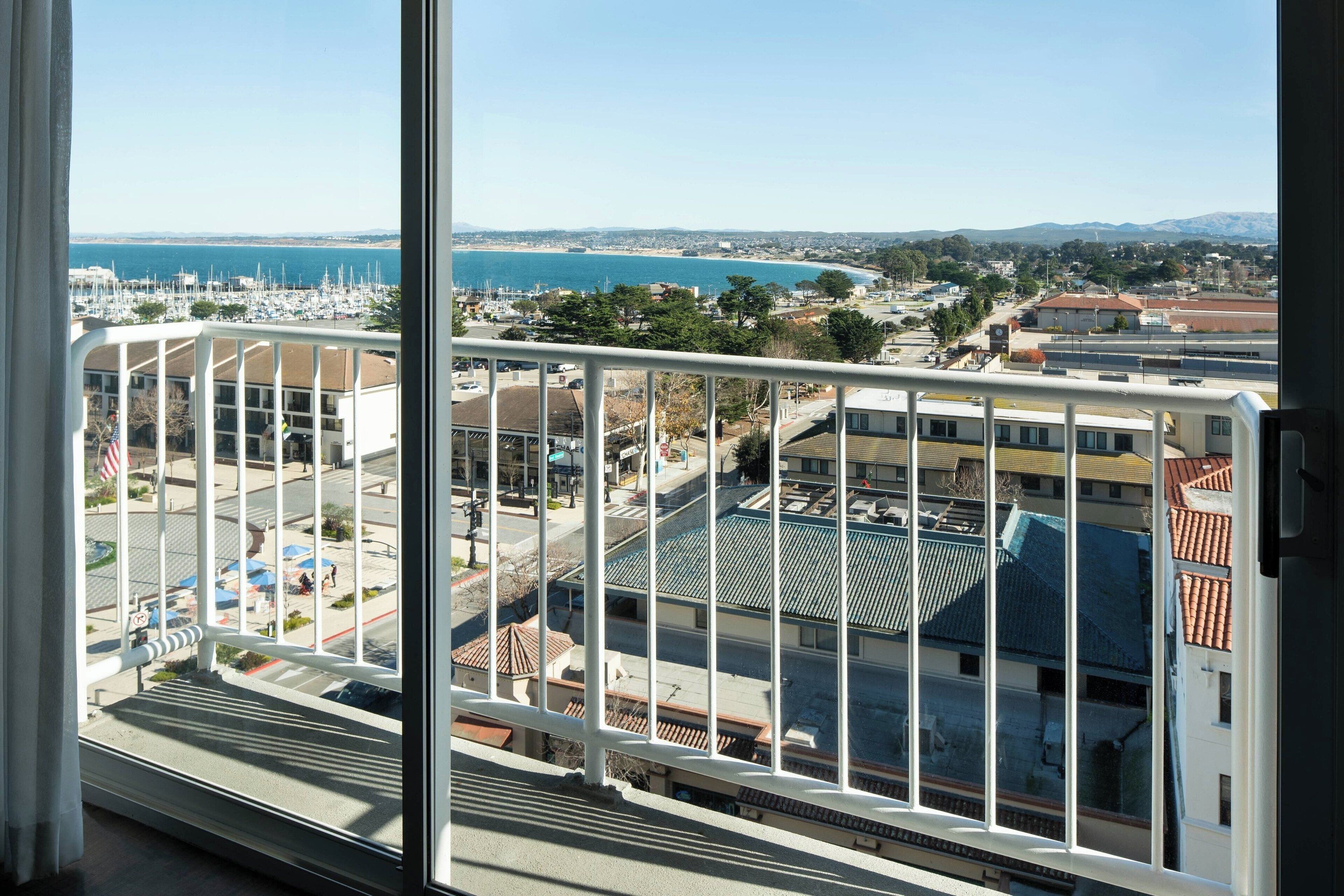 Varanda com vista para um porto, edifícios e uma costa distante.