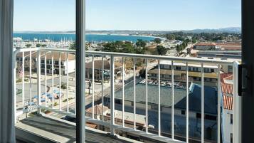 Un balcón con vista a un puerto deportivo, edificios y una costa lejana.