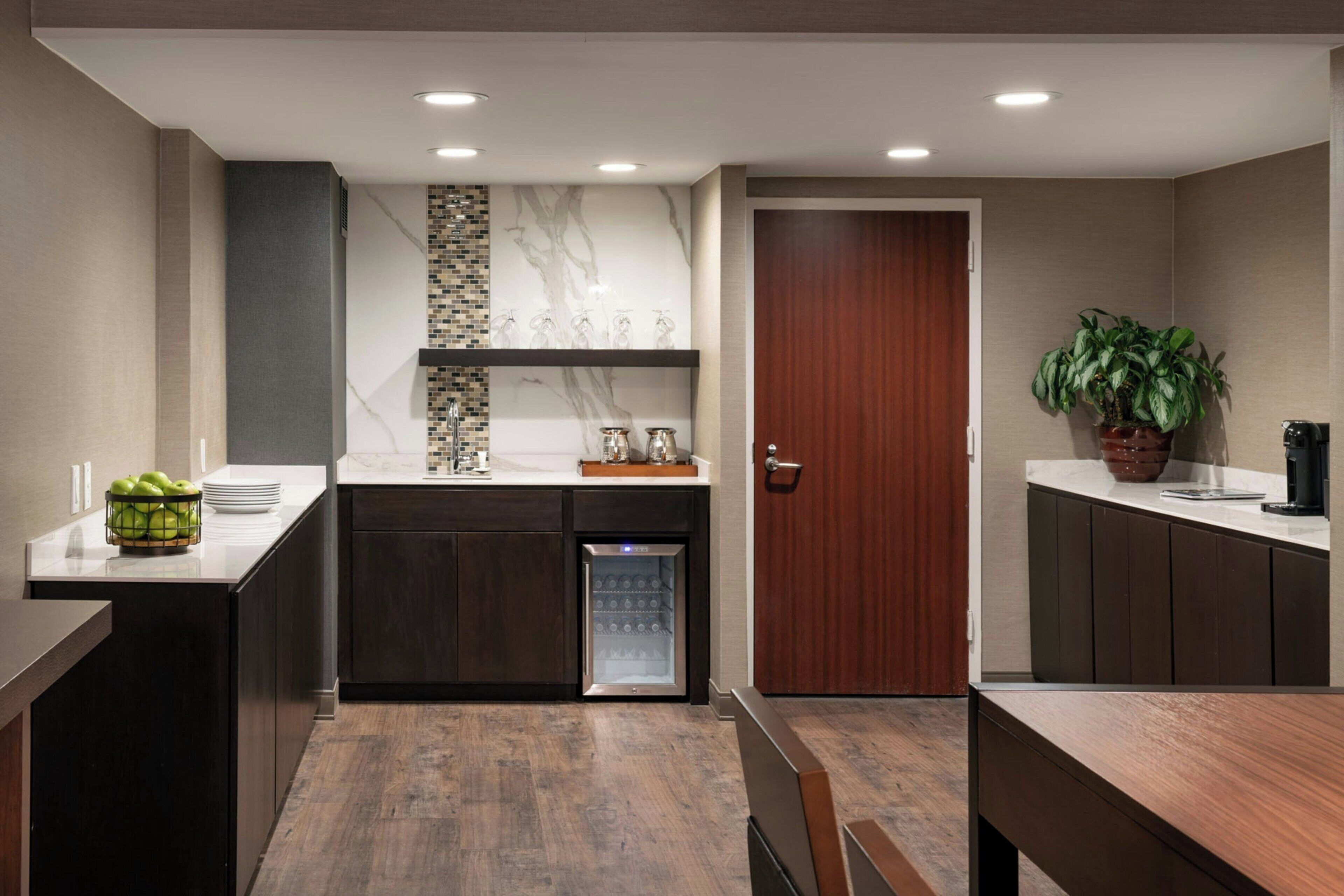 A modern kitchen with dark cabinetry, a marble backsplash, and a built-in refrigerator.