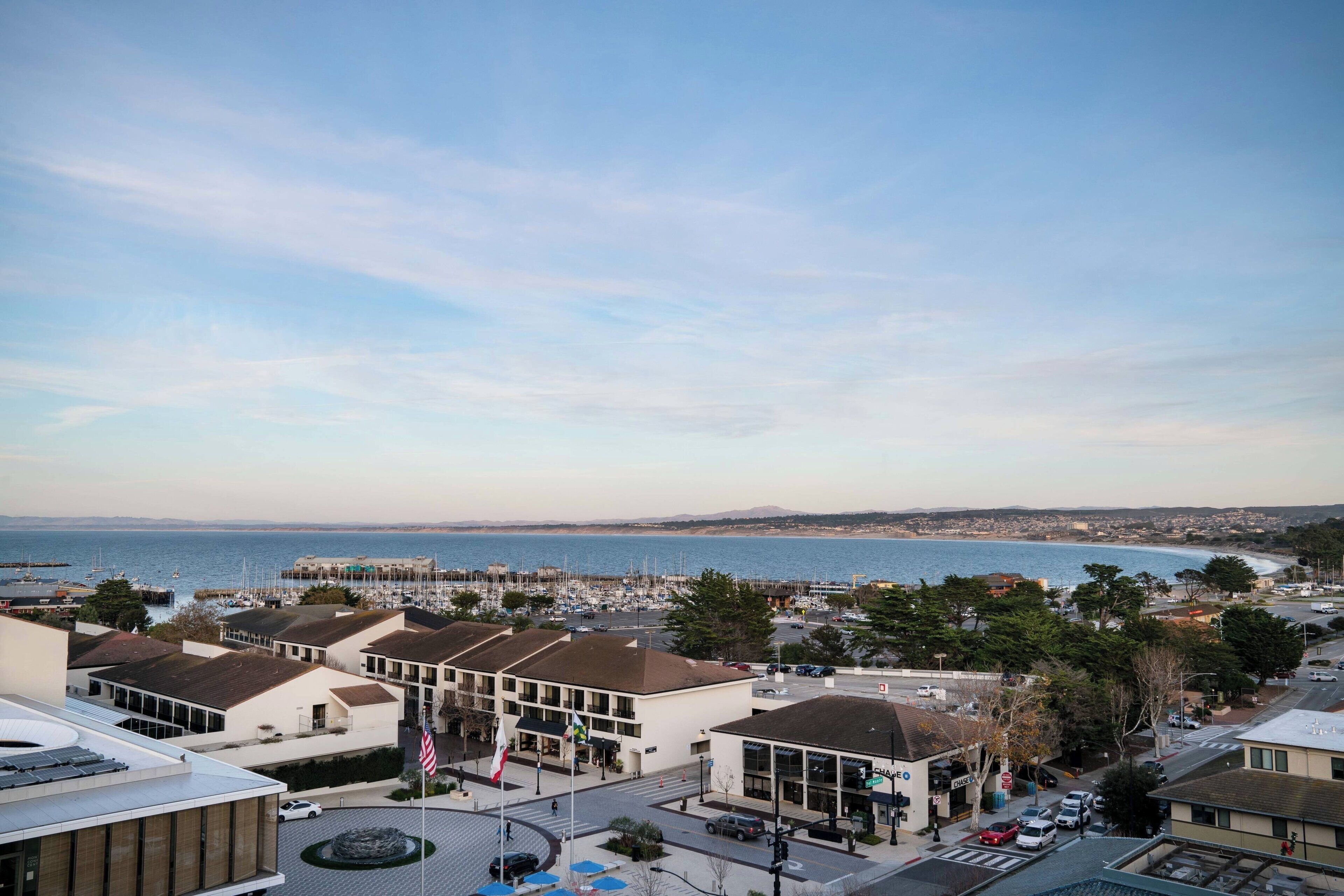 Un pueblo costero con edificios, un puerto deportivo y una vista despejada del mar.