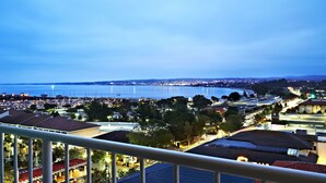 A coastal cityscape at dusk with a view of the sea and a marina.