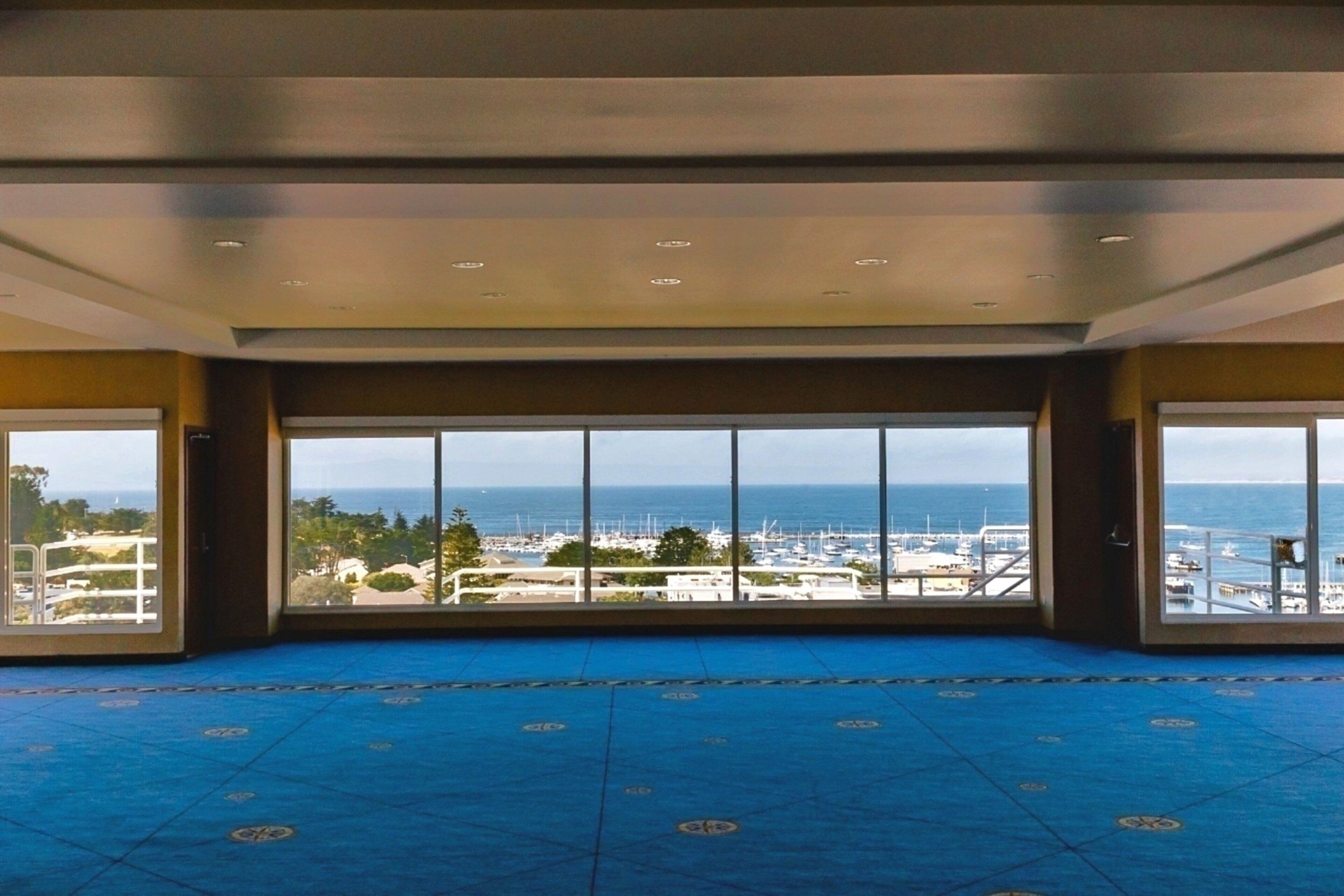 A spacious room with a large window offering a view of the sea and marina.