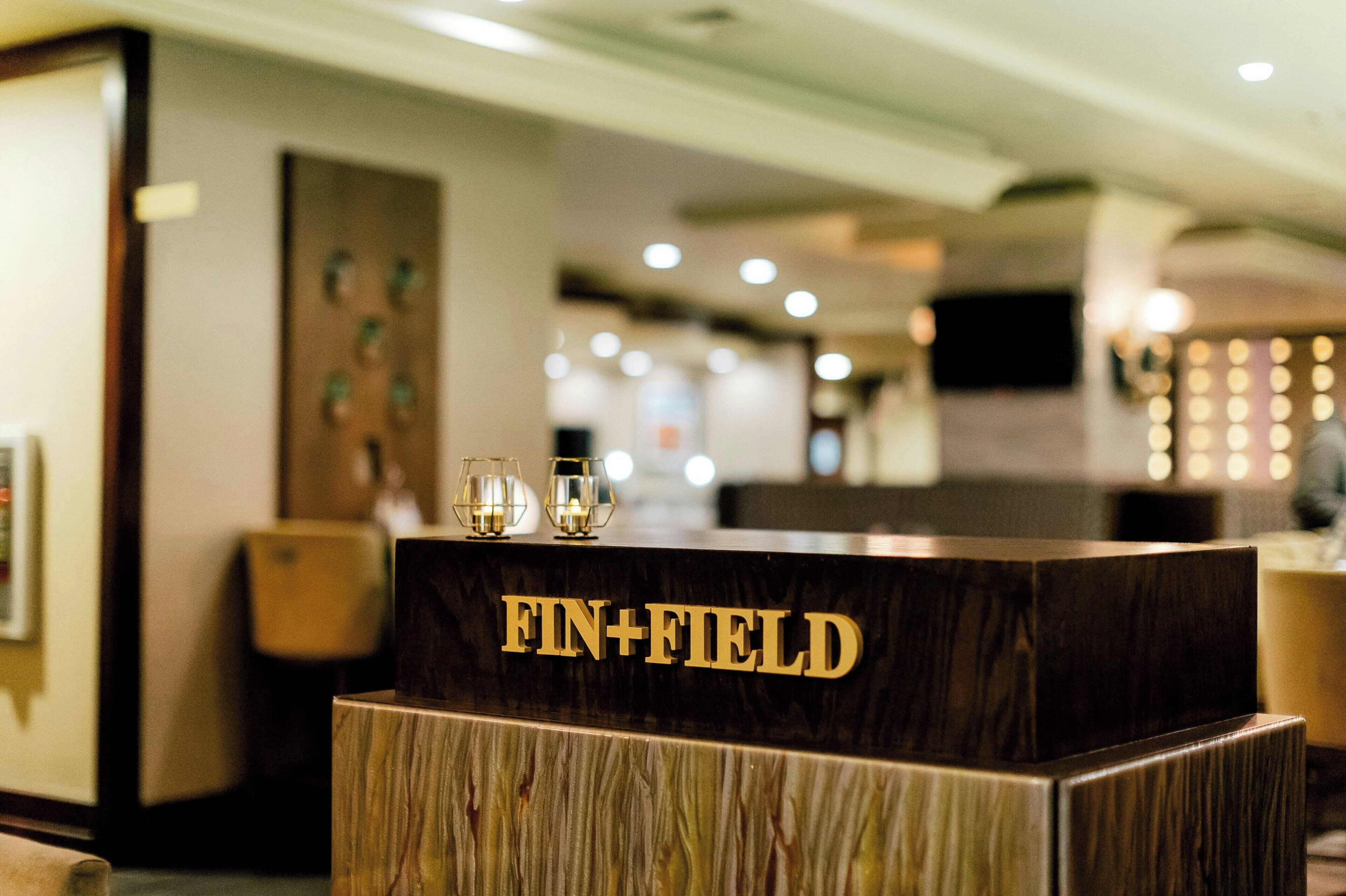 Un mostrador de recepción con el nombre "FIN+FIELD" en letras doradas.