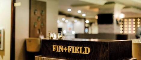 Un mostrador de recepción con el nombre "FIN+FIELD" en letras doradas.