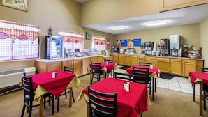 A restaurant with tables and chairs, a kitchen area, and a window with a view.