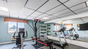 A gym with exercise equipment, a treadmill, and a mirrored wall.