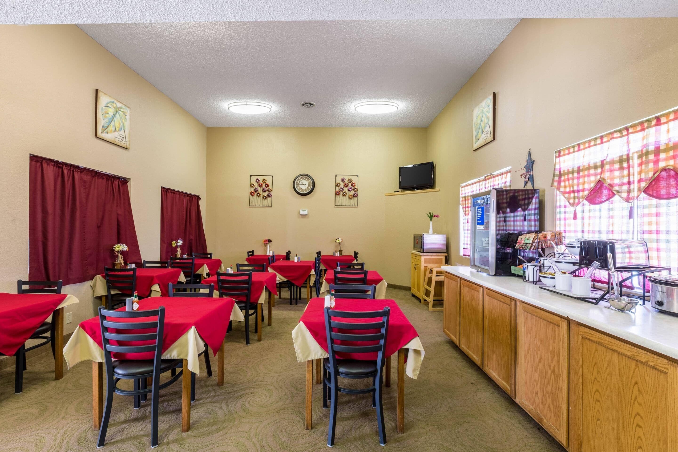 A dining area with tables and chairs, a counter with a cash register, and wall decorations.