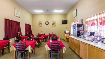 A dining area with tables and chairs, a counter with a cash register, and wall decorations.