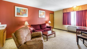 A furnished living room with a red wall, two framed artworks, a sofa, a coffee table, a lamp, and a window with curtains.