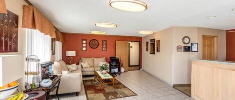 A spacious living room with a sofa, coffee table, and a dining area with a fruit bowl.