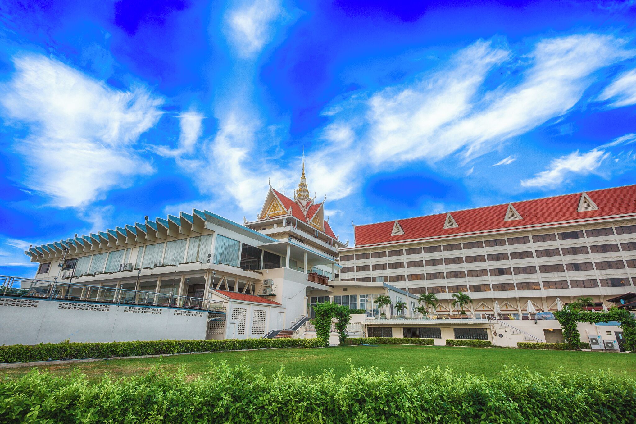 A modern building with a traditional Thai architectural style, featuring a prominent temple-like structure with a pointed roof and golden spire.
