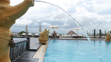 Una piscina al aire libre, sombrillas, sillones reclinables de piscina