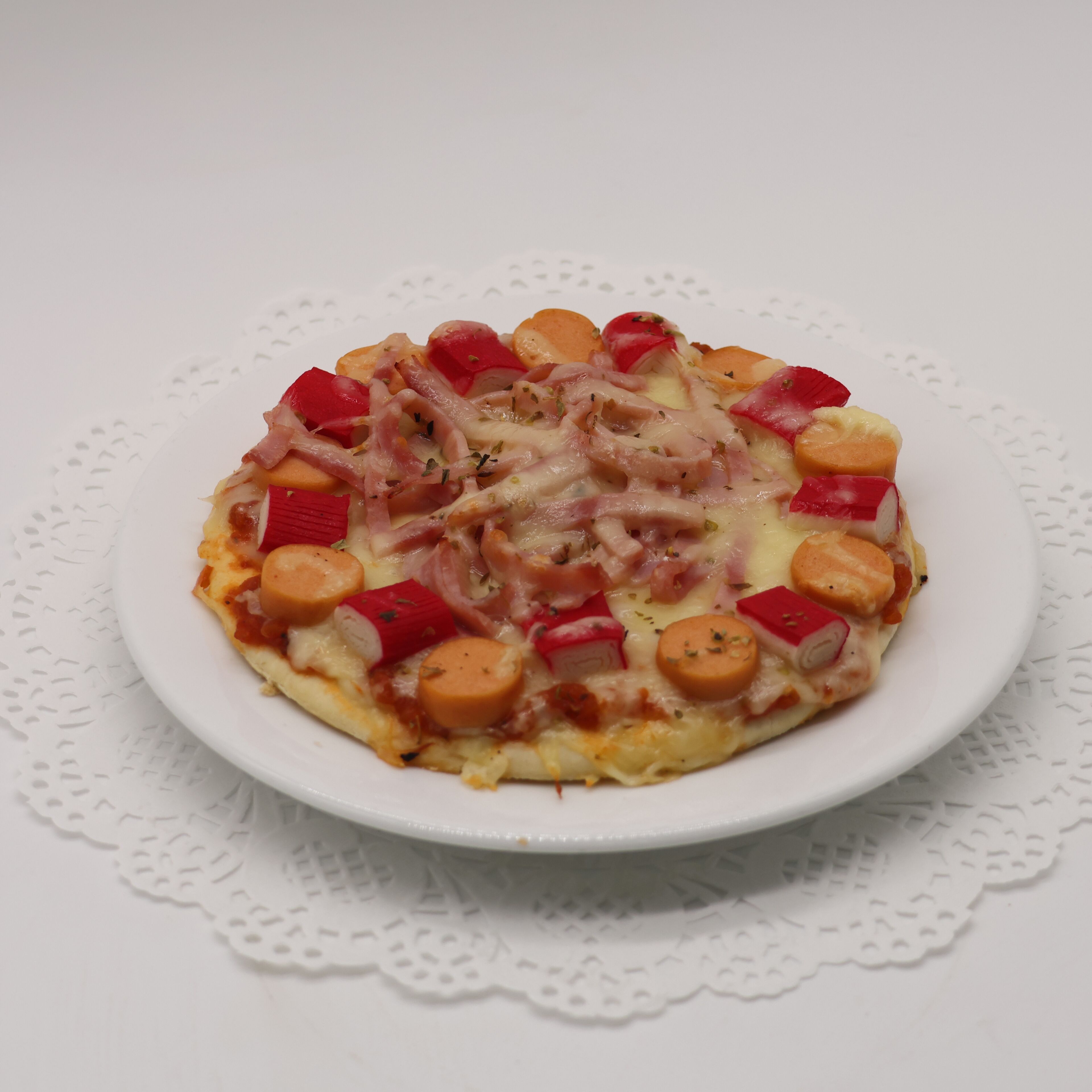 A pizza on a white plate with a doily underneath.