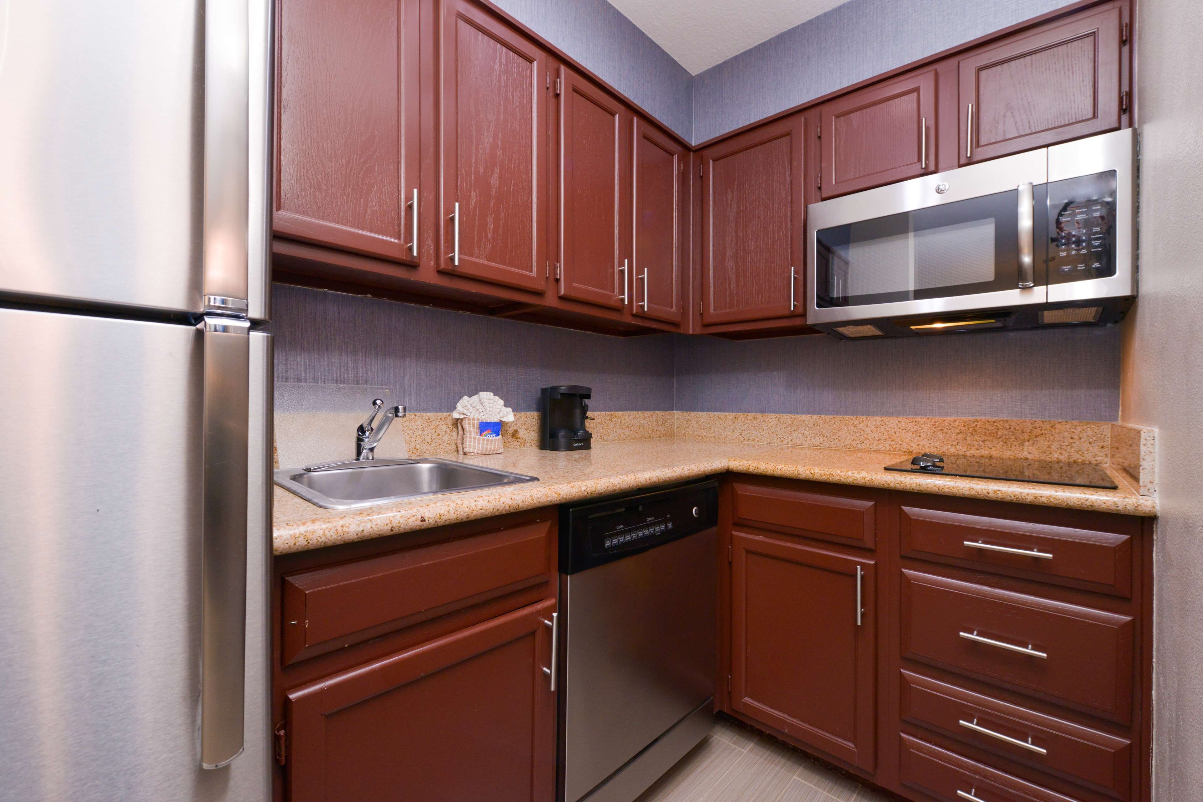 A kitchen with stainless steel appliances, wooden cabinets, and a granite countertop.