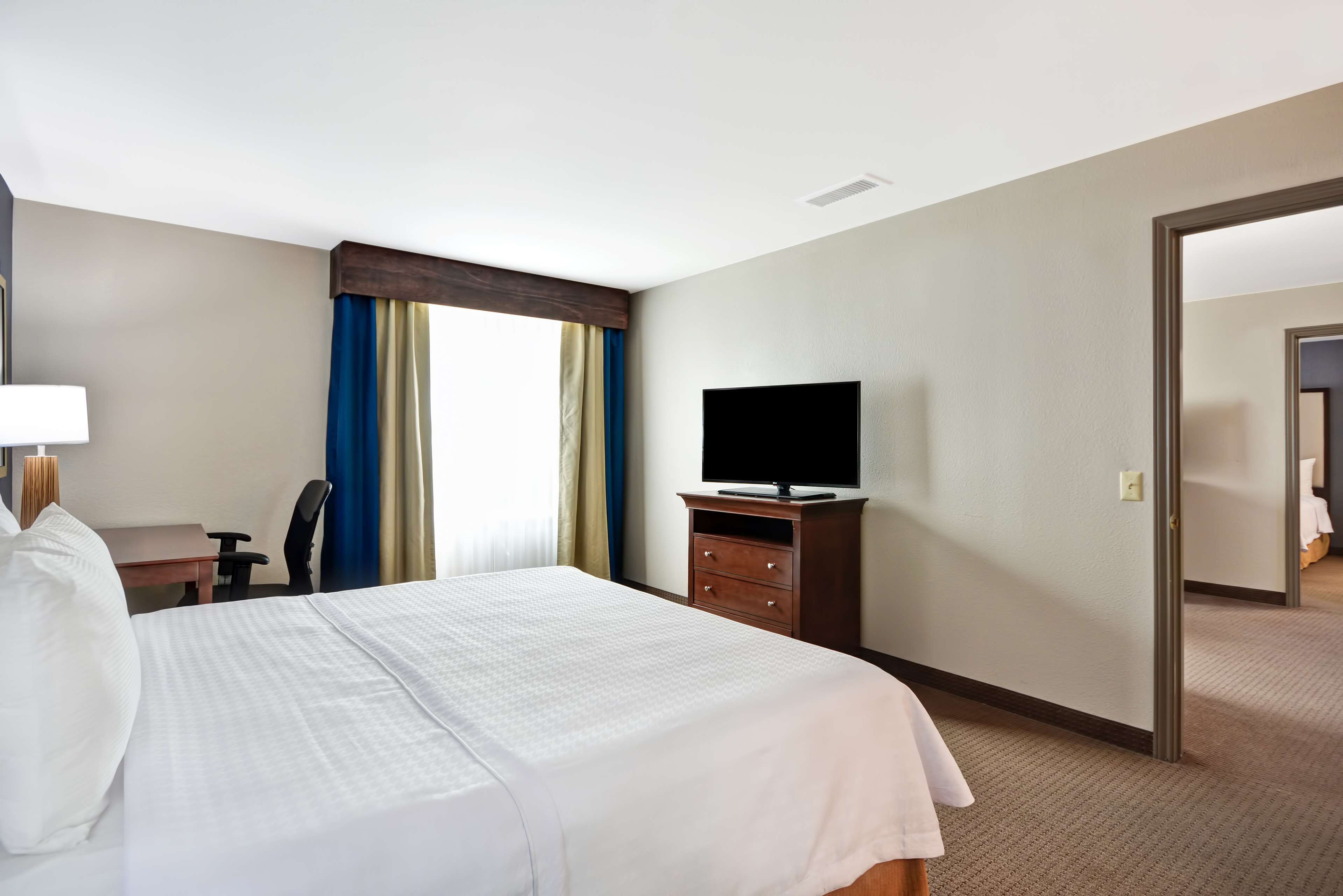 Une chambre d’hôtel équipée d’un lit, d’un bureau, d’une chaise, d’une télévision et d’une armoire.