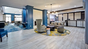 Un vestíbulo amplio con una decoración azul y blanca, que incluye una mesa de centro redonda, sofás y una alfombra estampada.