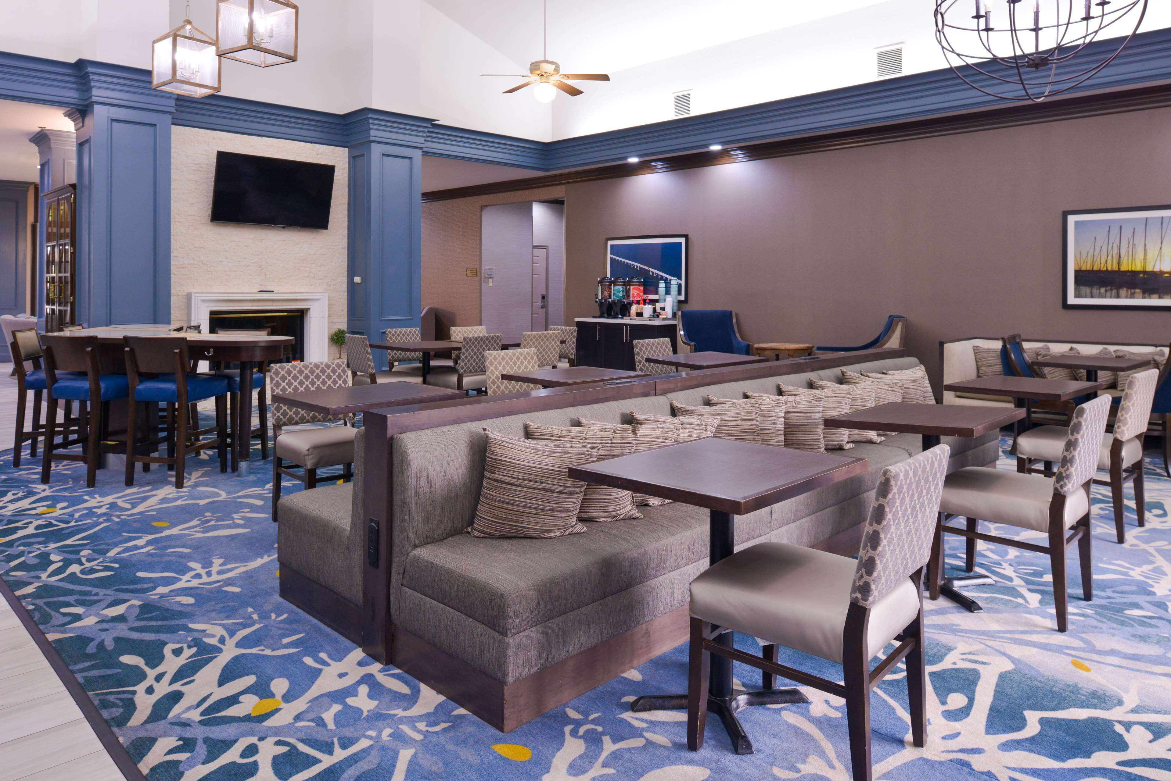 A hotel lobby with a fireplace, seating areas, and a bar.