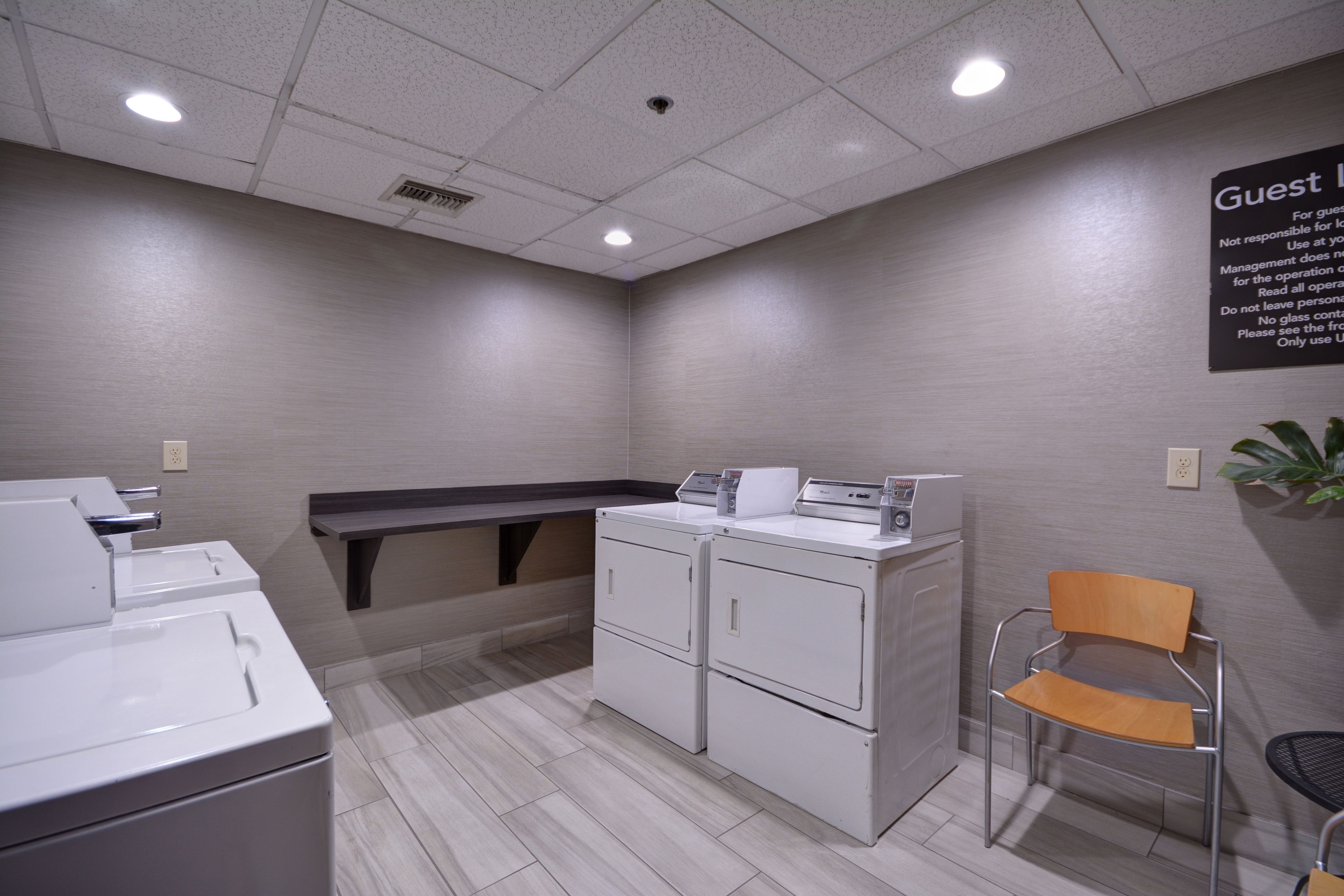 A laundry area with a washing machine, dryer, and a chair.