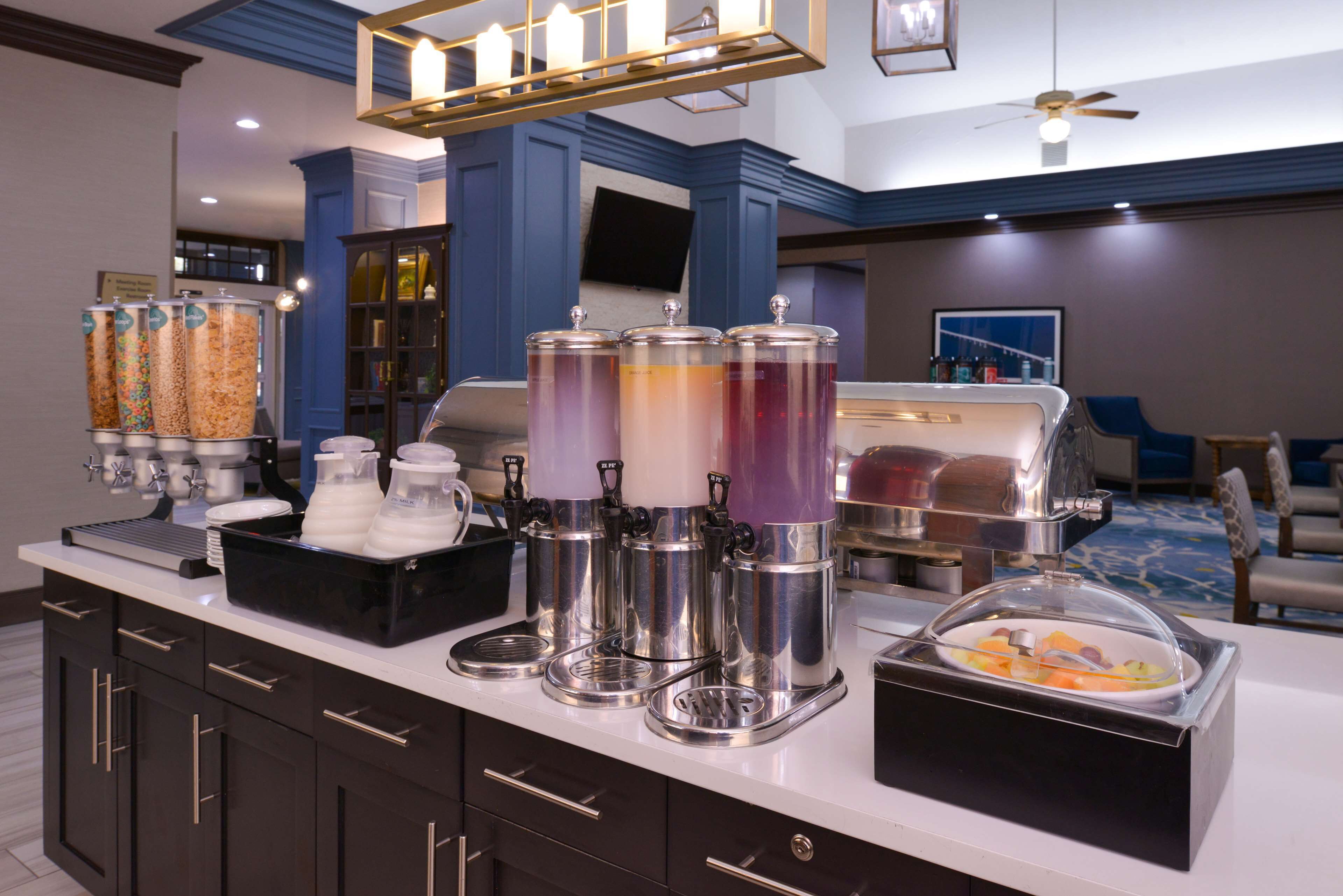 Een buffetopstelling met dispensers, een koffieapparaat en een schaal fruit.