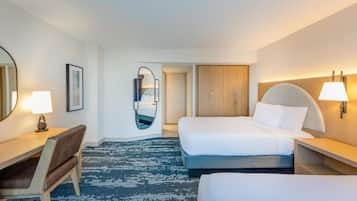 A hotel room with a bed, a desk, a chair, a wardrobe, and a mirror.