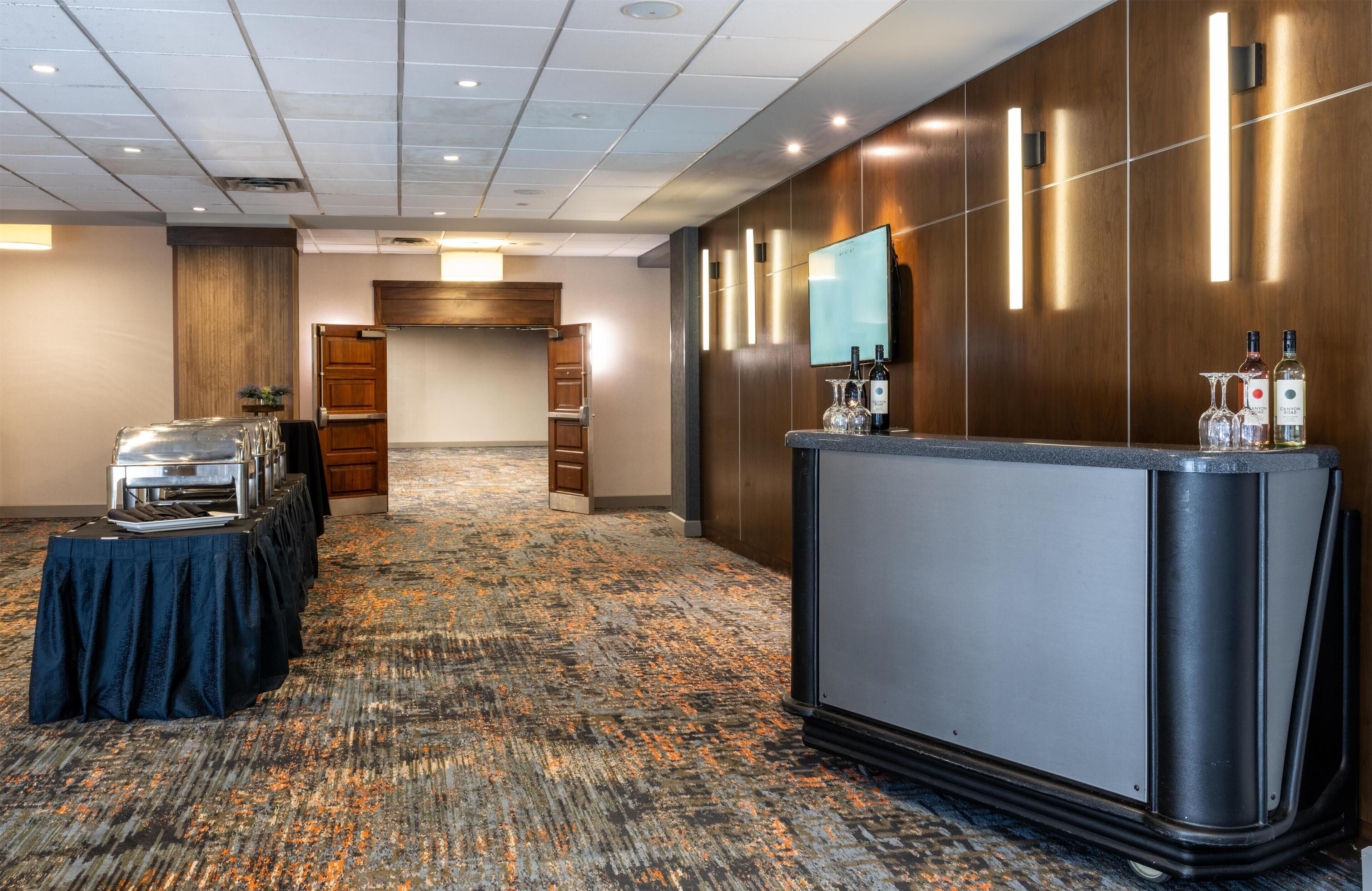 A conference room with a long table, a reception desk, and a television.