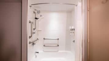 Une salle de bain moderne équipée d’une baignoire, d’une douche et de barres d’appui.