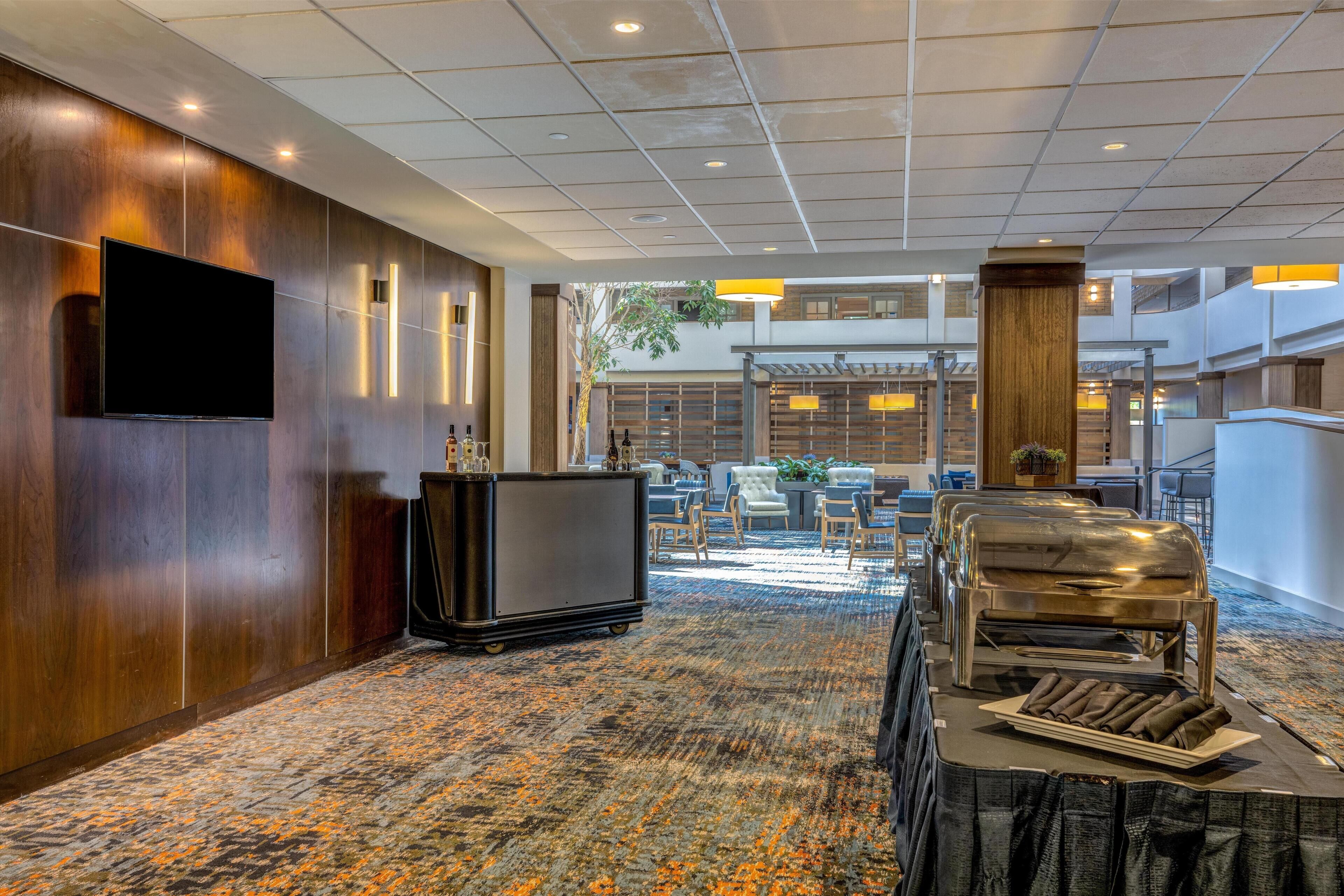 Eine Hotelhalle mit einem großen Flachbildfernseher, einer Rezeption und einem Buffetbereich mit Grill.