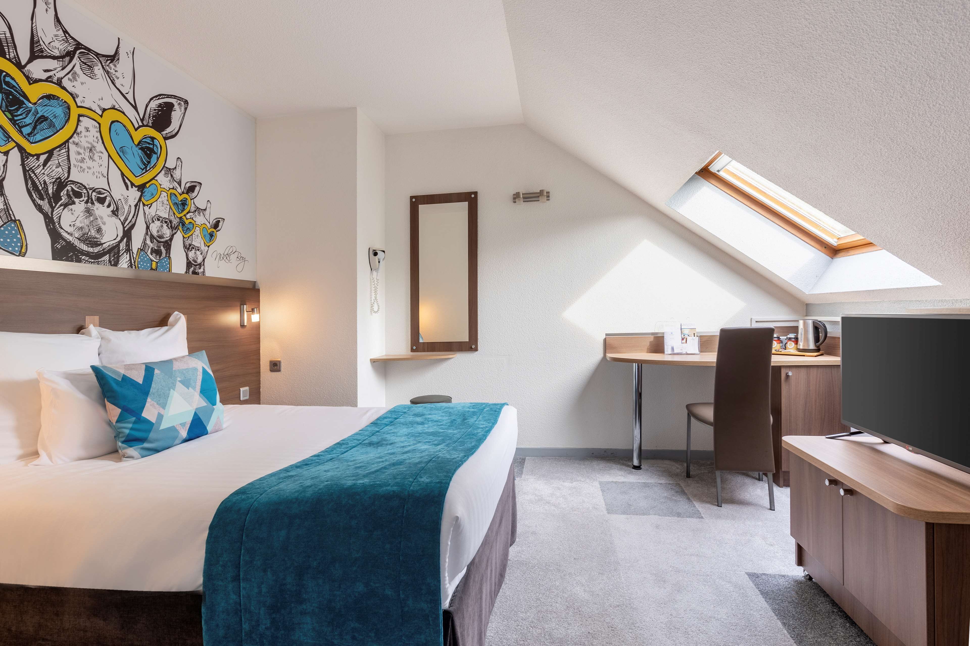 A hotel room with a bed, a desk, a chair, a television, and a skylight.