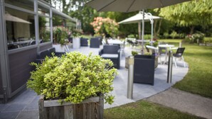 An outdoor patio area with a wooden planter, outdoor seating, and umbrellas. -  Sure Hotel by Best Western Lille Tourcoing (Bondues)