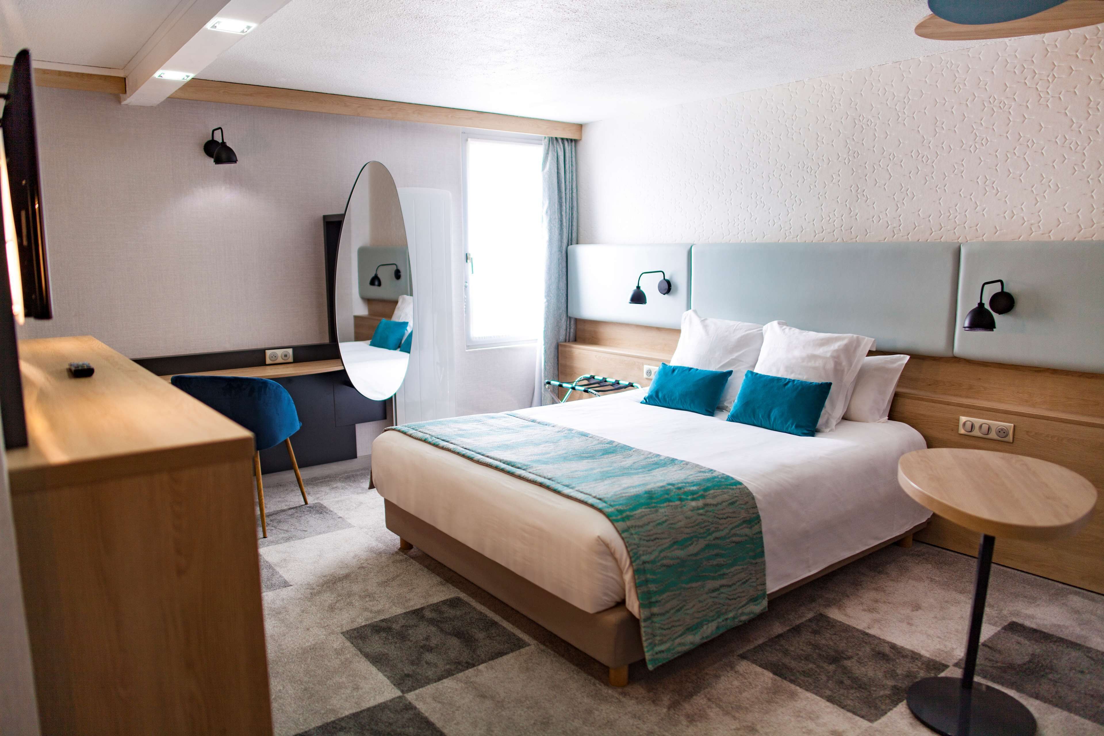 Una habitación de hotel moderna con una cama grande, un escritorio, una silla y una mesa redonda.