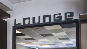 A lounge area with a checkered ceiling, a sofa, a table, and chairs. -  Sure Hotel by Best Western Lille Tourcoing (Bondues)