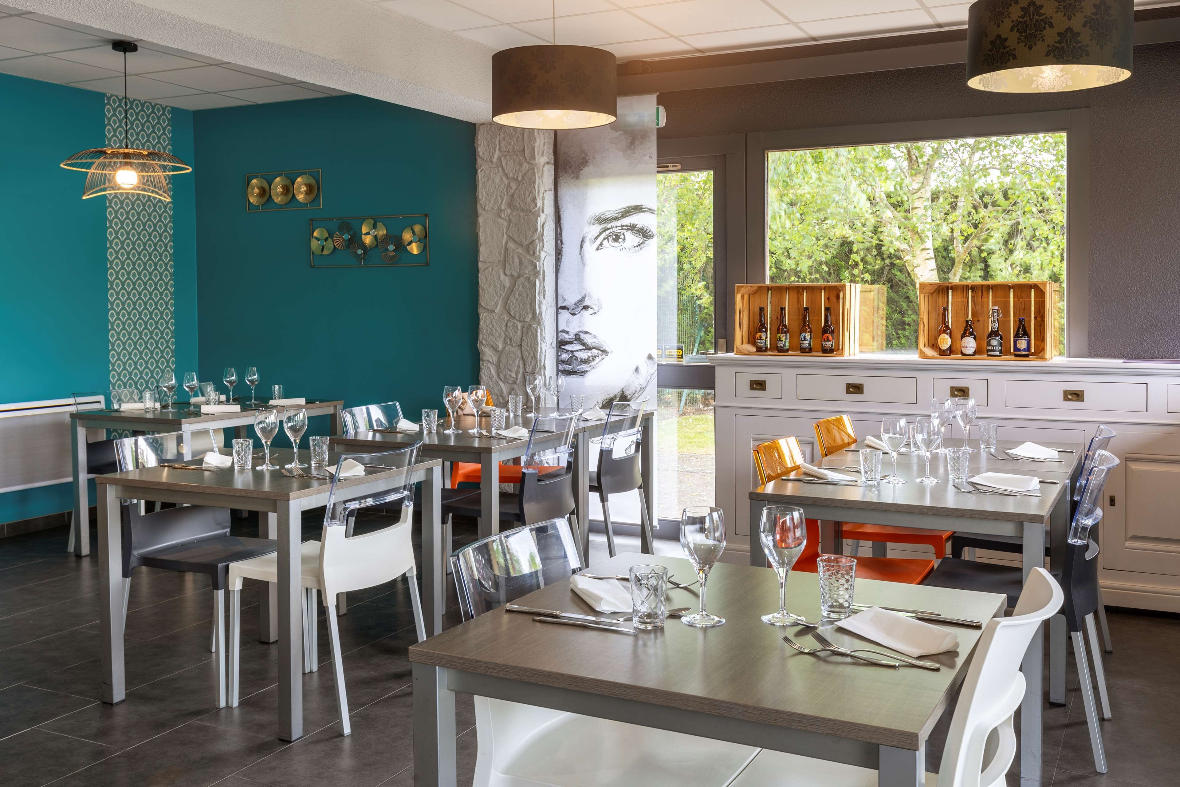 Zona pranzo moderna con diversi tavoli, sedie e un'ampia finestra che offre vista sul verde.