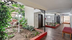 A hotel corridor with a garden area, wooden flooring, and a bench. - Coratel Plus Suites Wichita West Airport (Wichita)