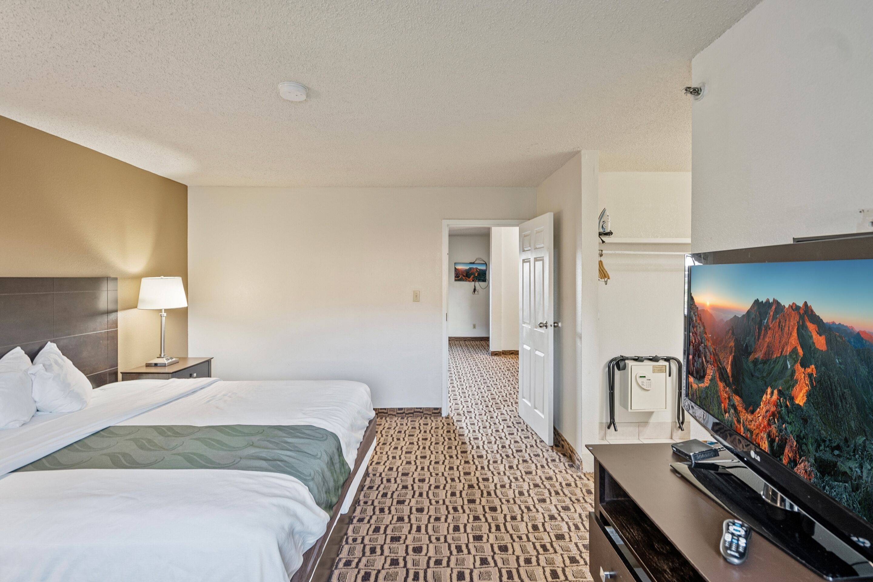 A hotel room with two beds, a TV, and a view of mountains.