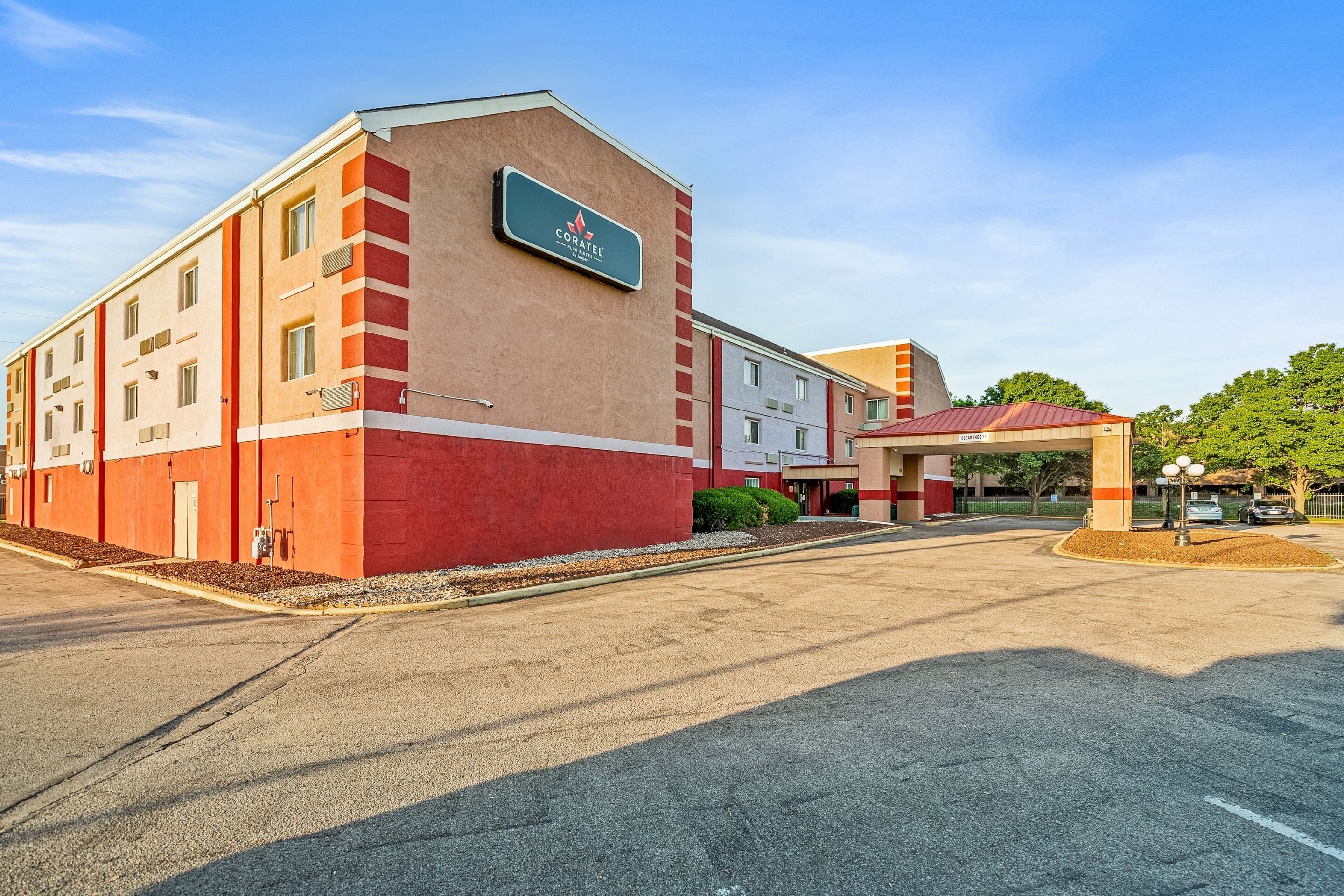 A hotel with a prominent sign, a parking lot, and a building entrance.
