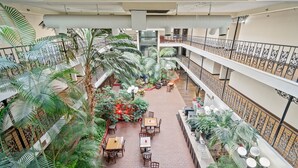 A multi-level atrium with indoor seating, palm trees, and a central staircase. - Coratel Plus Suites Wichita West Airport (Wichita)