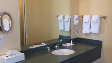 A bathroom with a large mirror, a sink, a towel rack, and a trash can.