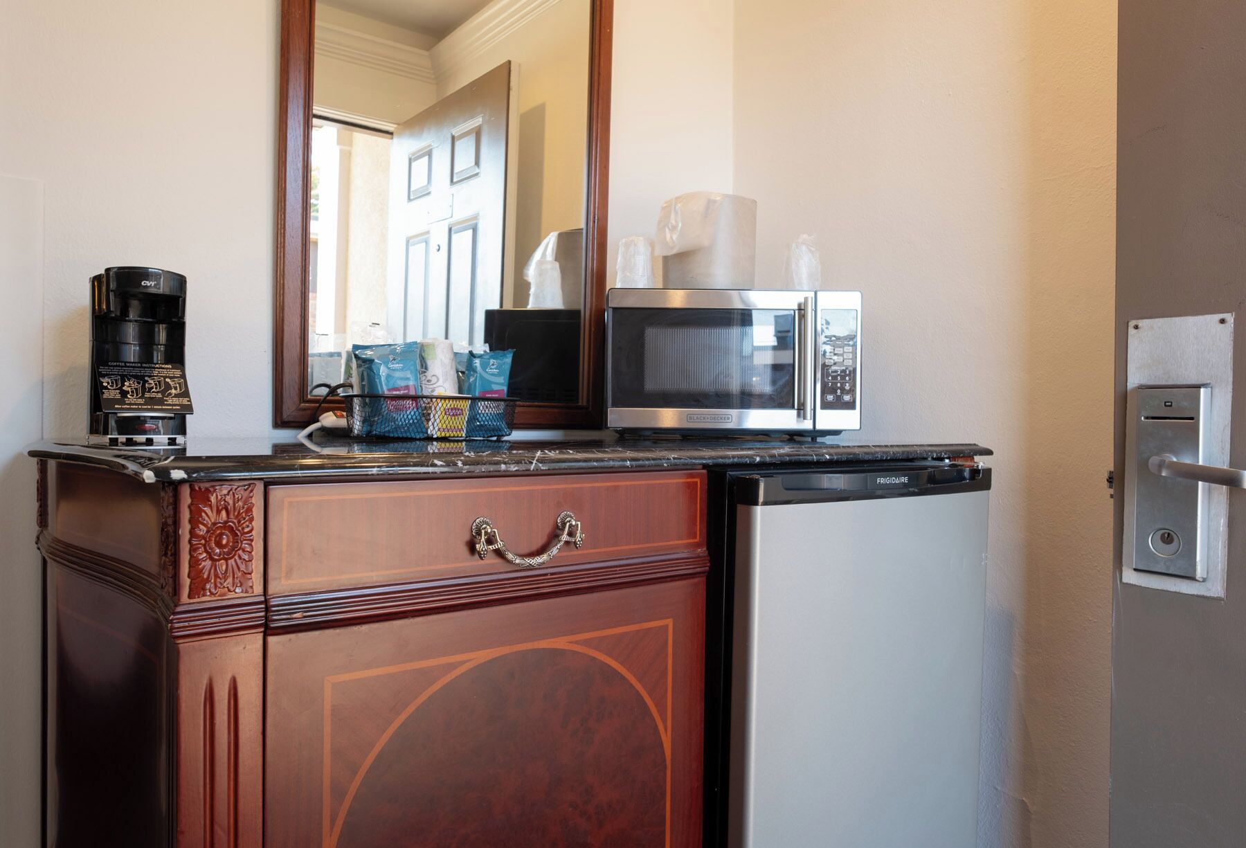 A kitchenette with a coffee maker, microwave, and refrigerator.