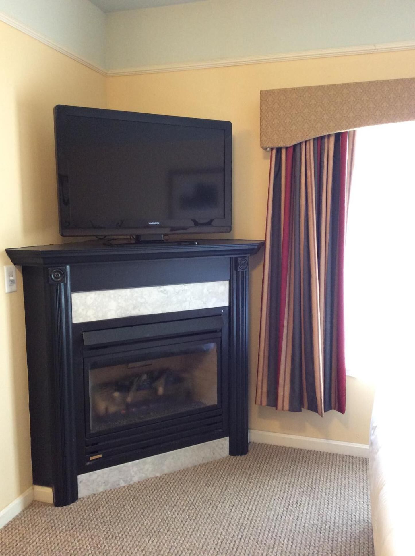 Un mueble negro para entretenimiento con un televisor de pantalla plana y una chimenea.
