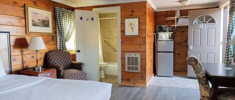 A room with two beds, a desk, a chair, a microwave, and a door marked with the number 185.