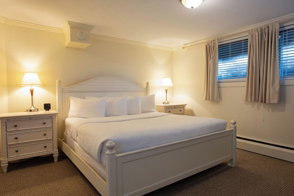 A neatly arranged bedroom with a single bed, two bedside tables, and a window with curtains.