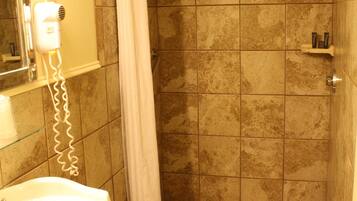 A bathroom with a shower, a sink, and a mirror.