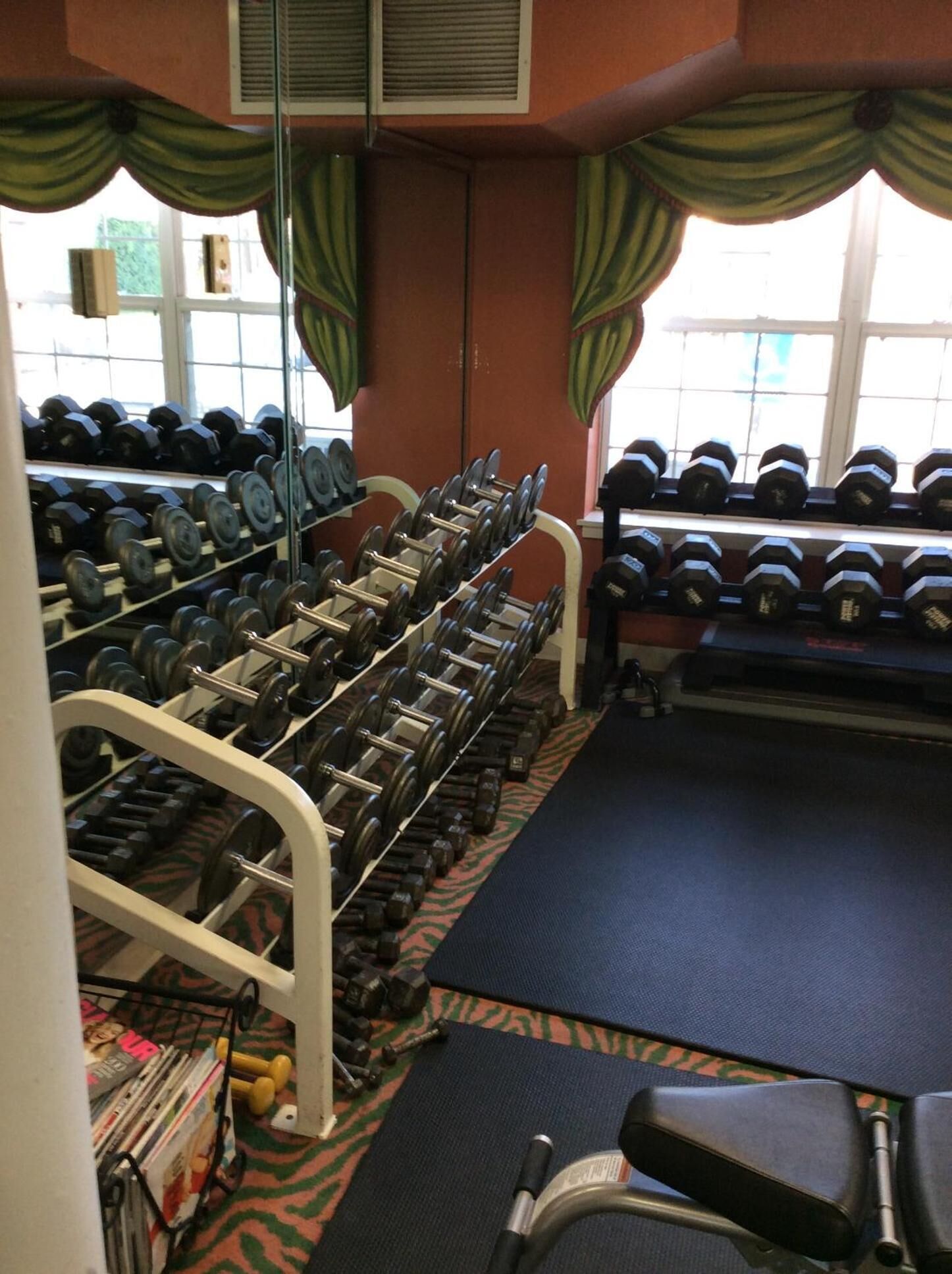 Ett gym med flera rader av hantlar, ett löpband och annan träningsutrustning.