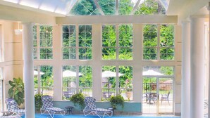 Uma área de piscina com vista ampla para o exterior, incluindo árvores e um alpendre com guarda-sóis.