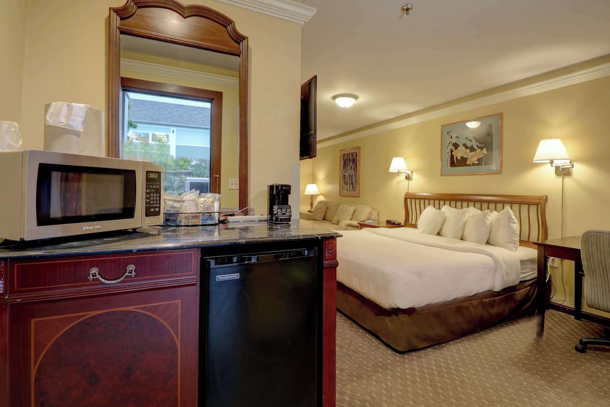 A hotel room with a bed, bedside lamps, a microwave, a coffee maker, and a TV.