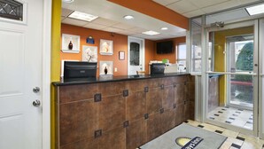 A reception area with a brown tiled counter, framed artwork on the wall, a television, and a glass door leading outside. - Days Inn by Wyndham Nashville Airport (Nashville)