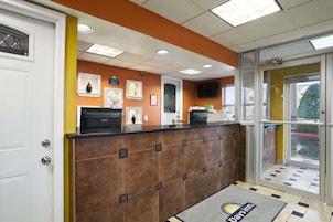 A reception area with a brown tiled counter, framed artwork on the wall, a television, and a glass door leading outside.