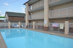 A swimming pool with a fenced area, a multi-story building with balconies, and a brick building in the background. - Days Inn by Wyndham Nashville Airport (Nashville)