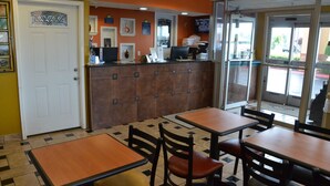 A restaurant interior with a counter, tables, and chairs. - Days Inn by Wyndham Nashville Airport (Nashville)
